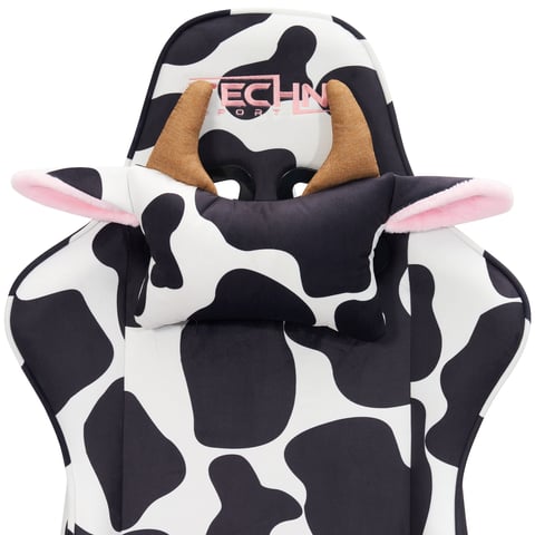 A plush toy cow character with black and white cow print fabric, pink inner ears, and tan horns, wearing a pink and black logo shirt.