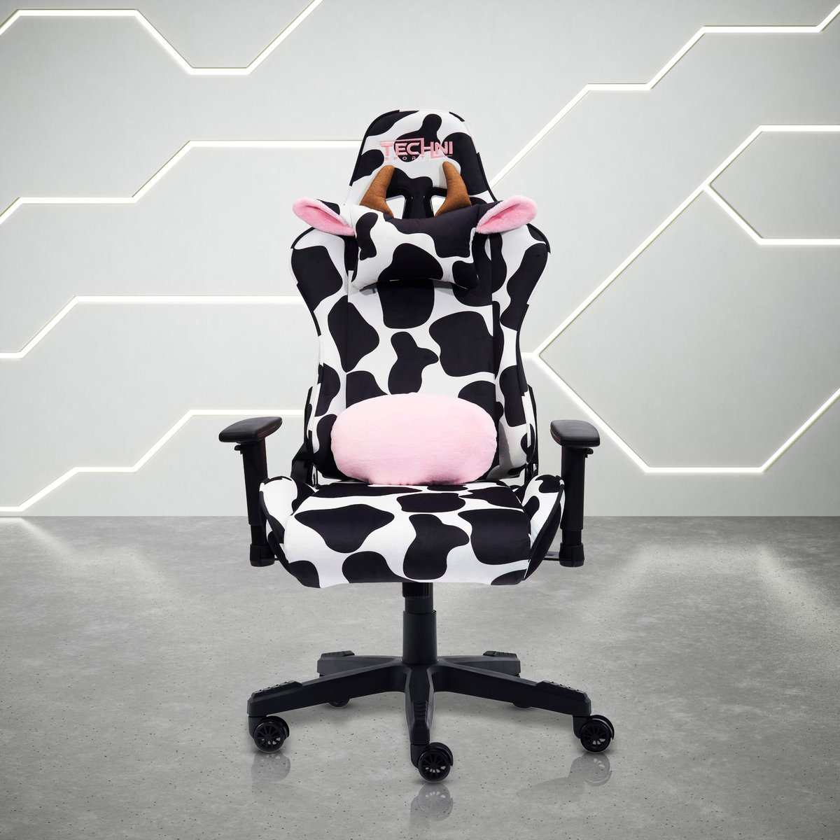 Gaming chair with cow-print black and white pattern and pink accents, featuring adjustable armrests and wheels
