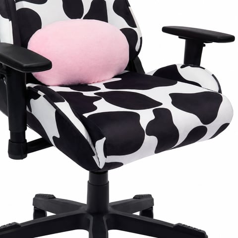 Gaming chair with black and white cow print upholstery, pink headrest pillow, adjustable armrests, and five-wheeled black base