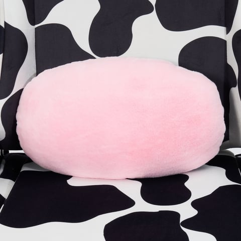 Pink round plush pillow on black and white cow-print fabric background